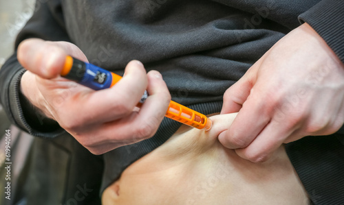 A diabetic man injecting himself with insulin before eating. Insulin injection close-up. photo