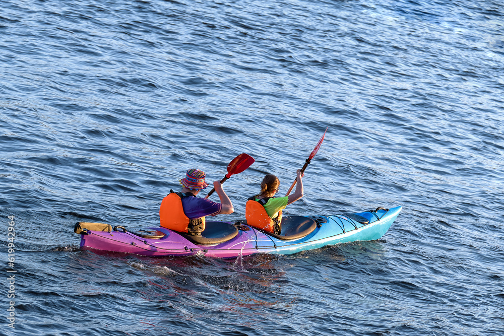 Obraz premium A couple of young people are kayaking on the water. Young family on active vacation.