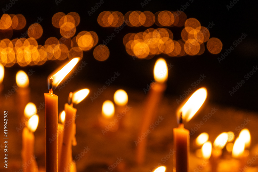 A lot of burning candles in the temple in the dark. The concept of religion, prayer and God. A lot of burning candles in the temple in the dark. The concept of religion, prayer and God.
