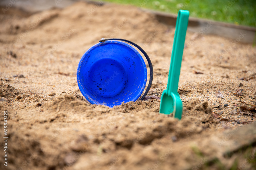 a close up of plastic toy bucket and spade in sandbox a close up of plastic toy bucket and spade in sandbox