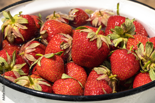 Freshly picked red ripe strawberries rinsed with running water. Macro shot of red berries washing. Wash fruits before eating concept