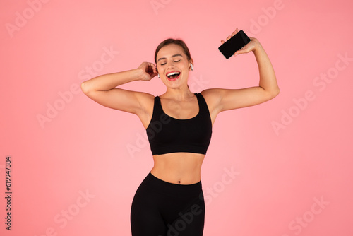 Cheerful Sporty Woman In Wireless Earphones Listening Music On Smartphone And Dancing