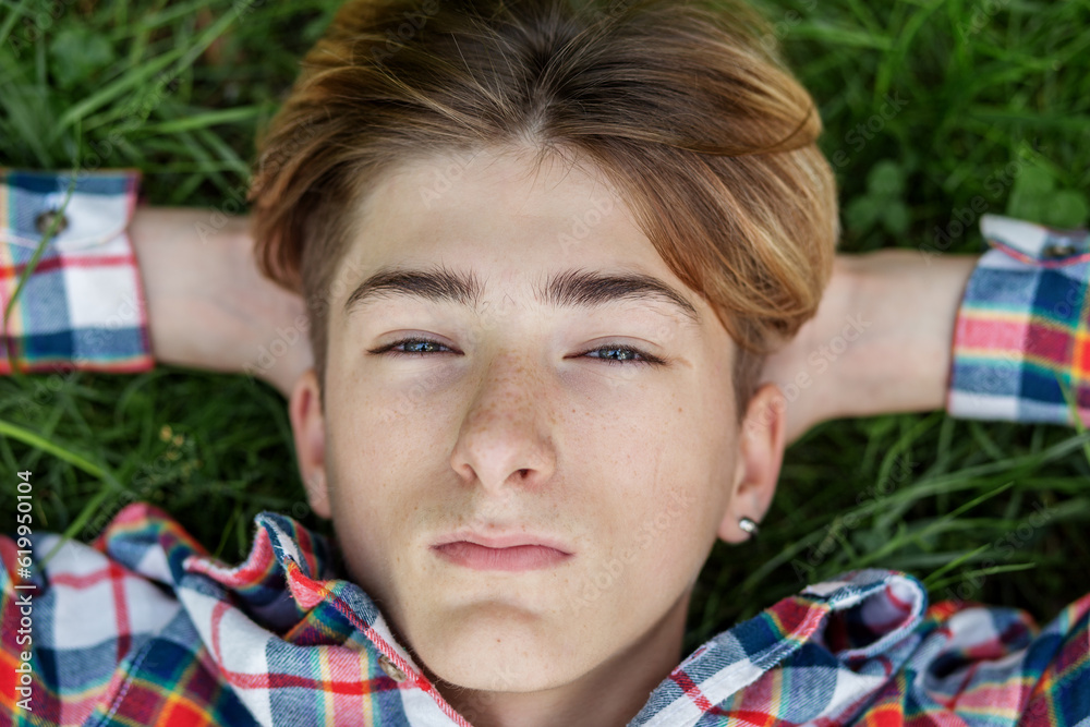 Portrait of serious teenager who lies in grass and rests. Gen Z. Identity development.