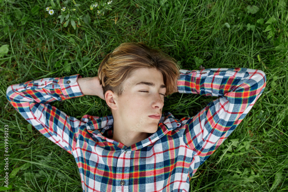 Portrait of serious teenager who lies in grass and rests. Gen Z. Identity development. Portrait of serious teenager who lies in grass and rests. Gen Z. Identity development.