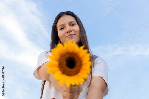 mujer joven, sonriendo y sosteniendo un girasol en un día soleado de primavera en un parque, enfoque selectivo, concepto de alegría, y belleza en primavera. paz, girasoles gigantes y amarillos. photo