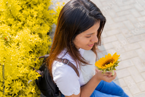 mujer joven, sonriendo y sosteniendo un girasol en un día soleado de primavera en un parque, enfoque selectivo, concepto de alegría, y belleza en primavera. paz, girasoles gigantes y amarillos. photo
