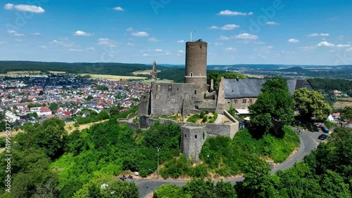 Ruins of medieval Gleiberg castle in Hesse, Germany, located on the top of a volcanic mountain. Aerial 4K panning video in summer photo