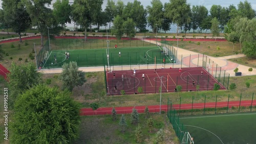 People training on open-air football and basketball courts in the park. Aerial drone view. photo