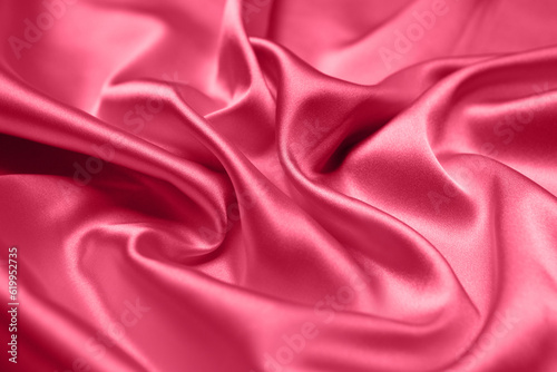 Viva Magenta toned red magenta fabric atlas. Close up pink silk satin texture for sewing. Abstract background wallpaper. Twisted folds cloth. Trendy color of the year 2023. Fashion color pattern
