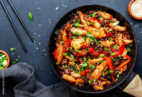Asian cuisine stir fried chicken, paprika, mushrooms, chives with sesame seeds in frying pan Fototapet
