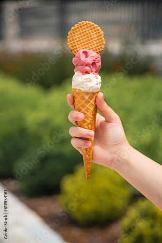 he child eats  tastes and licks ice cream in a cone against the background of nature