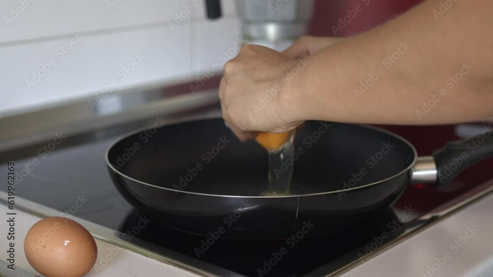 Preparing fried eggs in a frying pan. Video of an unrecognizable person