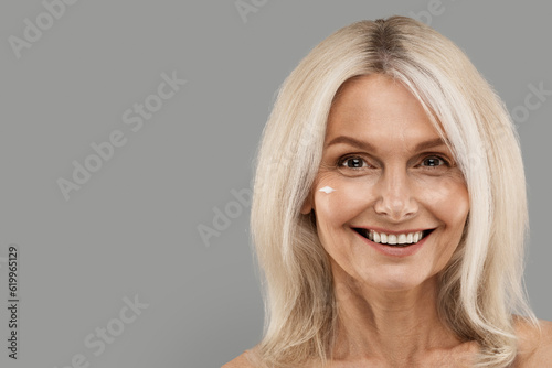 Skin Nourishing Concept. Beautiful Mature Woman With Moisturising Cream On Face
