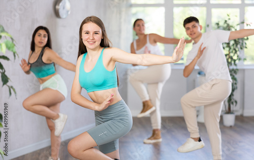 Cheerful teen girl enjoying while training movements of modern group dance in choreography class ..