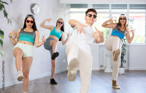Portrait of cheerful teenage guy practicing krumping movements during group dance lesson in studio