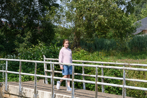 A teenage girl walks on a bridge over a river