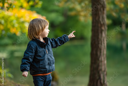 Adorable toddler boy admiring the Balsys lake, one of six Green Lakes, located in Verkiai Regional Park. Child exploring nature on autumn day in Vilnius, Lithuania.