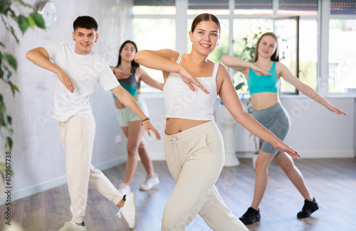 Group of energetic girls and guys learning dance at dance class