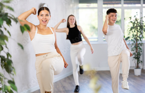 Group of happy young sports people exercising dancing in modern gym studio