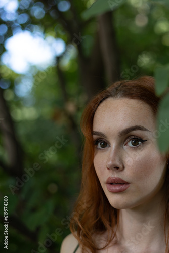 very beautiful freckled white woman with long red hair in a garden