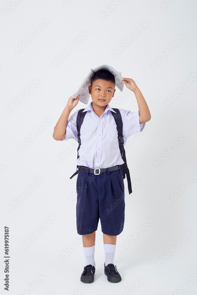 A young Asian cute boy standing in a Thai school uniform with a backpack bag and book on a white background banner A young Asian cute boy standing in a Thai school uniform with a backpack bag and book on a white background banner