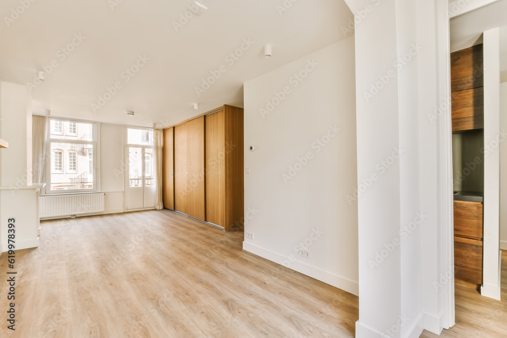 an empty living room with wood flooring and large windows in the room is white walls, hardwood floors and wooden doors an empty living room with wood flooring and large windows in the room is white walls, hardwood floors and wooden doors