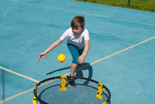 child playing sports game spikeball, spikeball. the boy is hitting the yellow ball in a miniature volleyball analog outside. photo