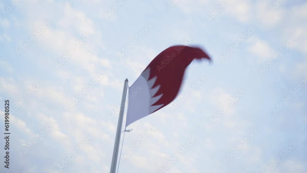 The Bahrain flag in the breeze under a blue sky The Bahrain flag in the breeze under a blue sky