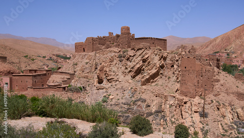 Ruins of a kasbah standing among residential houses in a modern village in Atlas mountains, Morocco. Authentic Berber architecture, houses built from a red clay. Before earthquake of September 2023.