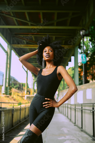 Fashion outdoor street style portrait Beautiful young African American woman posing outside on urban city landscape summer day wearing total black high leather boots. © Алина Троева