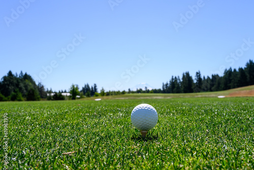 Closeup of golf ball teed up  scenic landscape in the background  recreation on a sunny summer day 