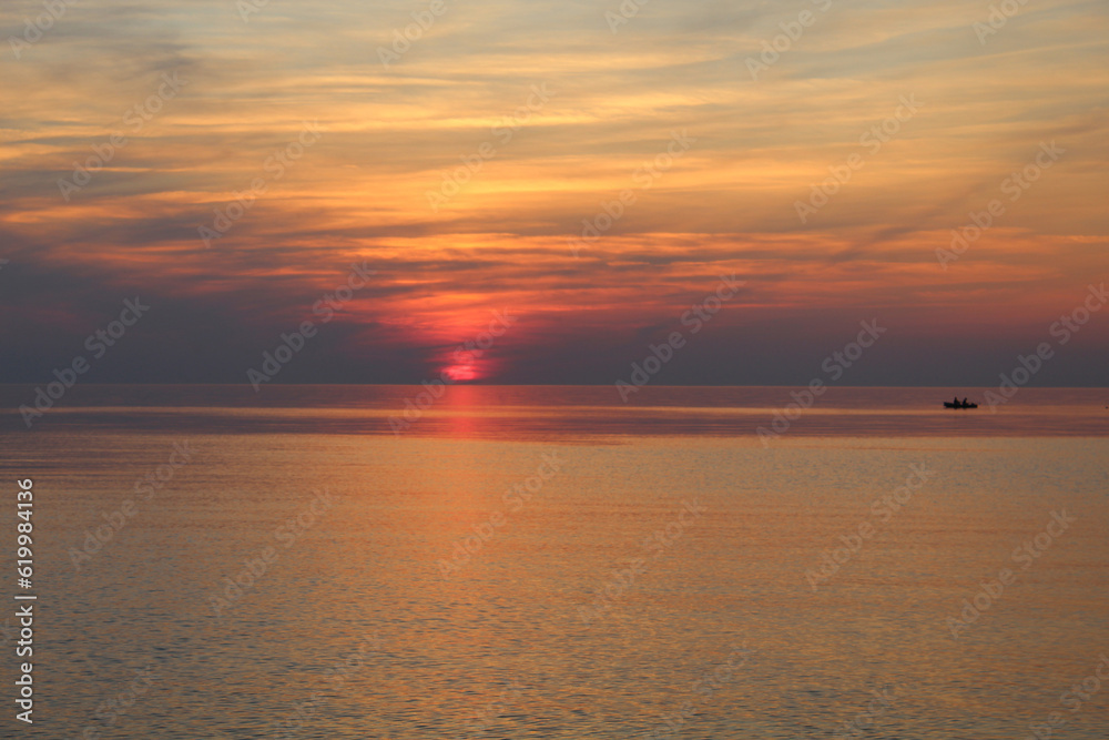 Sunset at the Baltic Sea in Saulkrasti, Lativa with a small boat on the horizon