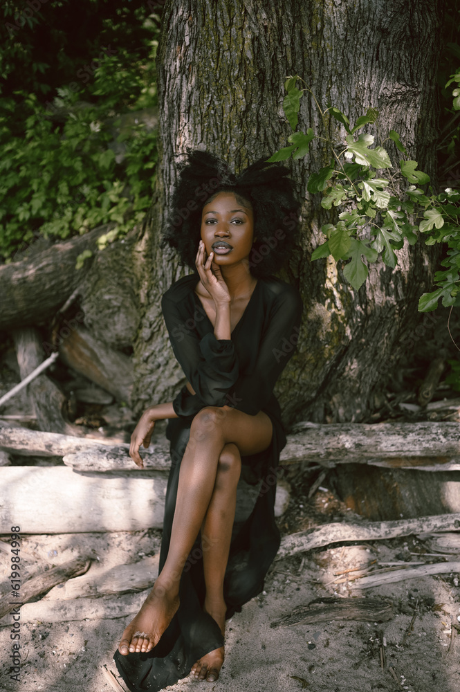 Fashion outdoor beach portrait Beautiful young African American Black woman posing outside on sandy coast with big green trees on sunny summer day. Cosmetology, natural skin body care and spa Fashion outdoor beach portrait Beautiful young African American Black woman posing outside on sandy coast with big green trees on sunny summer day. Cosmetology, natural skin body care and spa