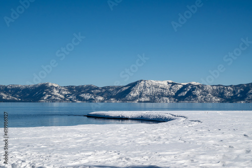 Frozen shore of Lake Tahoe in the winter, featuring cloudless blue sky and water copy-space, near Tahoe City, California side
