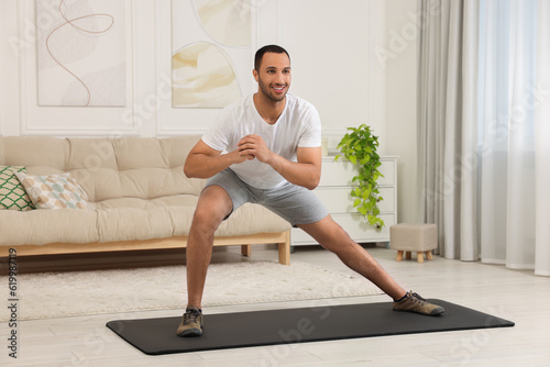 Man doing morning exercise on fitness mat at home