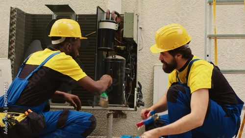 Knowleadgeable engineers assembling professional pressure indicator to check liquids and gases in air conditioner. african american mechanic cleans layer of built up dirt and dust in condenser. photo