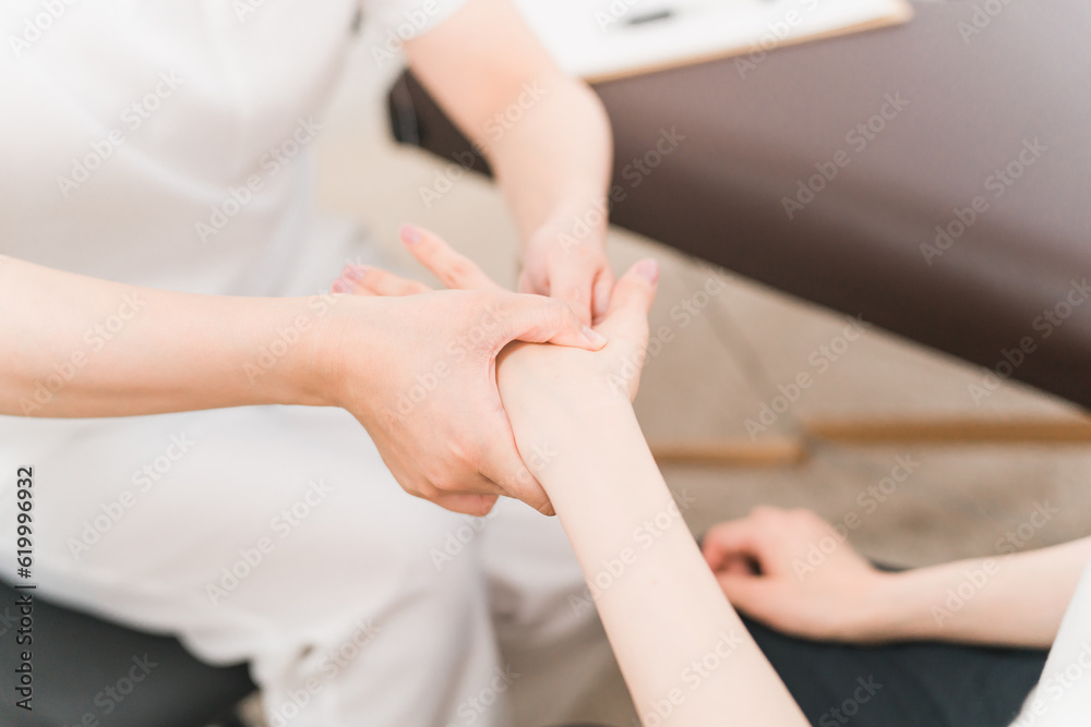 Fototapeta premium 整体・マッサージ・ボディケアを受ける女性と整体師・セラピスト(ハンドマッサージ)