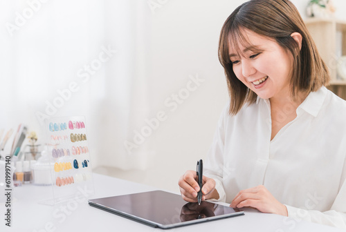 ネイルサロンでタブレットの契約書に電子サインするカウンセラースタッフと相談する日本人女性
 photo