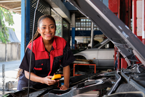 One Black female professional automotive mechanical worker checks an EV car battery and hybrid engine at a maintenance garage, expert electric vehicle service, and fixing occupations auto industry.