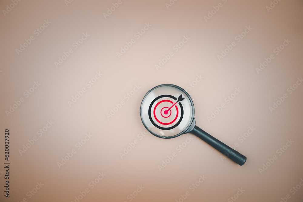 Target board inside magnifier glass for focus business objective with copy space. Idea of leading to a goal learn to plan, achieve investment strategy success and improve performance.