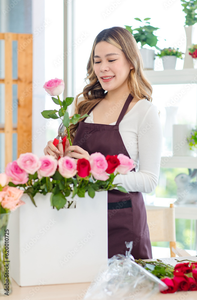 Asian professional successful female florist designer flower shop owner entrepreneur decorating pink roses bouquet in floral garden store studio