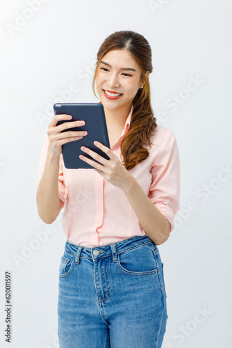 Portrait isolated cutout studio shot of Asian female businesswoman model in casual outfit standing smiling holding black blank screen tablet computer for copy space advertising on white background