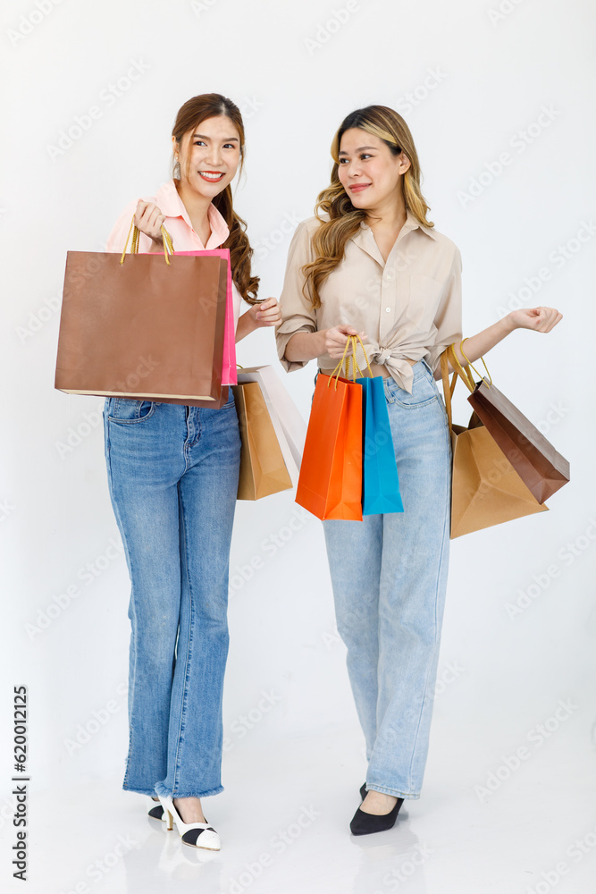 Portrait isolated cutout studio full body shot of two Asian cheerful female clients customers shoppers in casual outfit buying holding paper shopping bags in department store on white background Portrait isolated cutout studio full body shot of two Asian cheerful female clients customers shoppers in casual outfit buying holding paper shopping bags in department store on white background