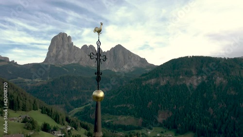 Aerial drone shot of a catholic church top cross with the Italian dolomites alps mountains in the background 03