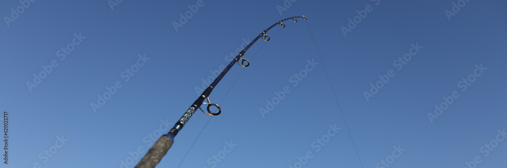 Fishing rod on sea beach on blue sky background Fishing rod on sea beach on blue sky background