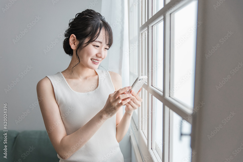 家でスマホを使う笑顔のアジア人女性(SNS・動画・ゲーム)
家でスマホを使う笑顔のアジア人女性(SNS・動画・ゲーム)