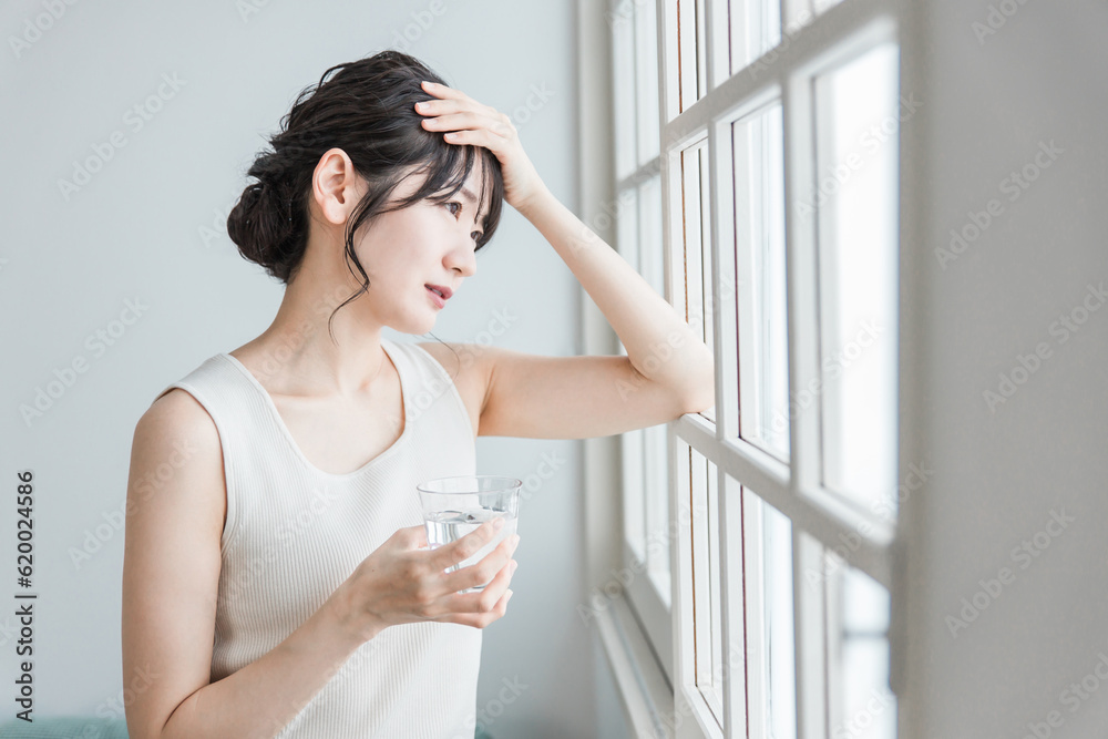 朝、体調不良・発熱・偏頭痛に悩むアジア人の女性
