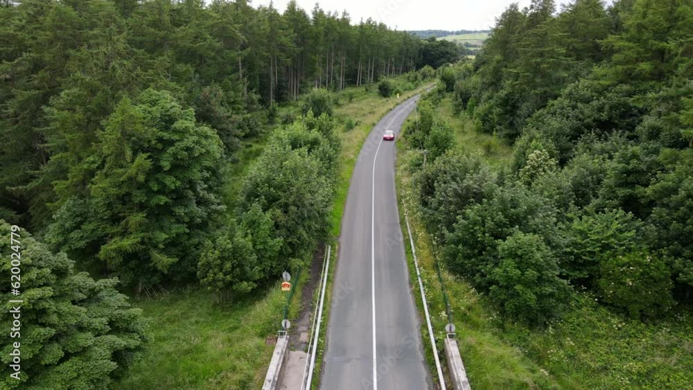 An electric Tesla car drives along road in summertime in Ireland. An electric Tesla car drives along road in summertime in Ireland.