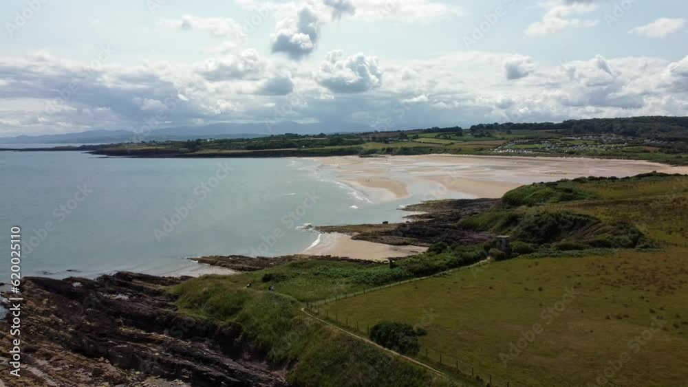 Traeth Lligwy idyllic rocky coast shoreline aerial descending view to green pasture on rocky cliffs edge Traeth Lligwy idyllic rocky coast shoreline aerial descending view to green pasture on rocky cliffs edge