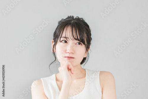 頬杖をついて考える・悩むアジア人女性（美容・ダイエット・エステ・脱毛）

